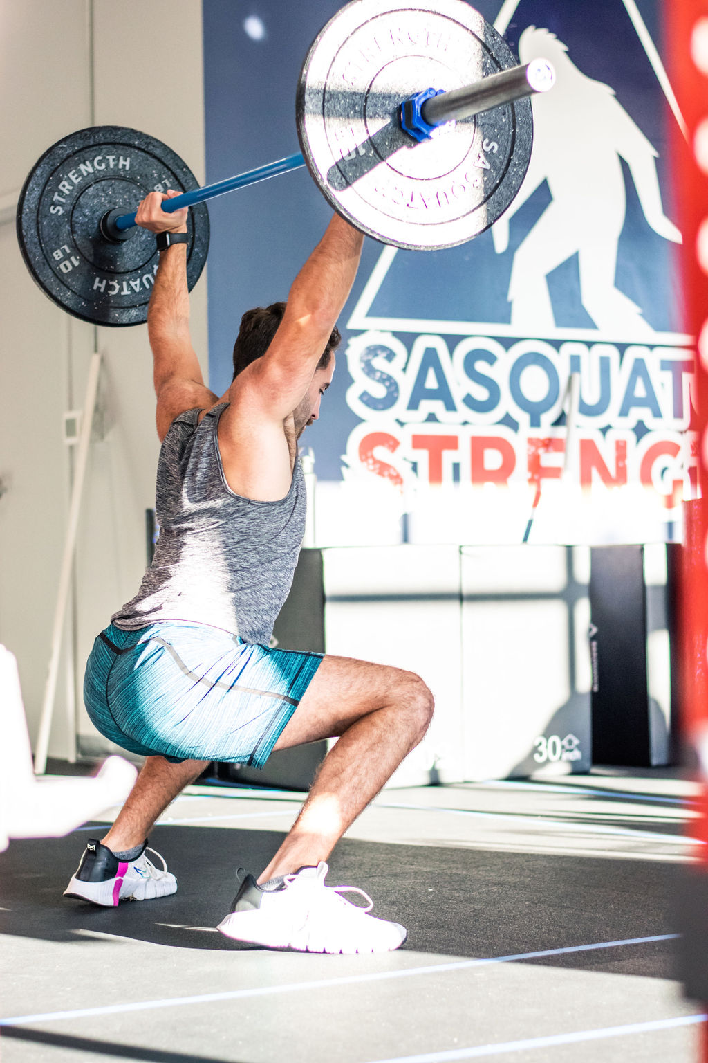 Member lifting a barbell overhead during strength training at Sasquatch Strength near Sammamish